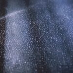 Close-up of shimmering bokeh lights on a textured dark surface creating an abstract pattern.