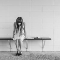 worried girl, woman, waiting, sitting, thinking, worry, black and white, sad, expression, people, person, depression, sadness, emotion, unhappy, adult, depressed, grief, frustration, despair, human, sad girl, problem, stressed, young, female, girl, long hair, dress, bench, concrete, wall