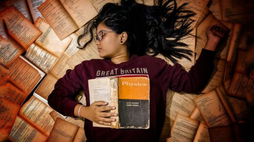 woman in red long sleeve shirt holding orange and white book