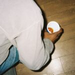 person in gray pants holding white plastic cup