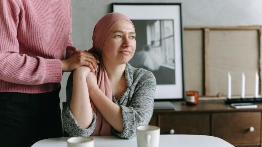 A supportive moment indoors featuring a cancer patient comforted by a friend, conveying emotion and care.