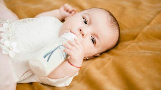 baby in white dress lying on yellow textile