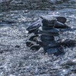 black stones on body of water during daytime