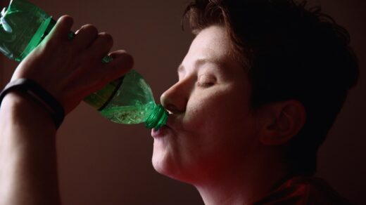 woman drinking from green plastic bottle