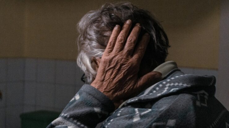 an older woman covering her face with her hands