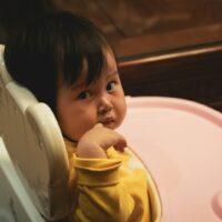 baby in white and pink high chair ready to poop