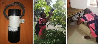 Prokopack aspirator (a vacuum-like device) to collect mosquitoes from a black, cylindrical resting shelter placed under dense vegetation