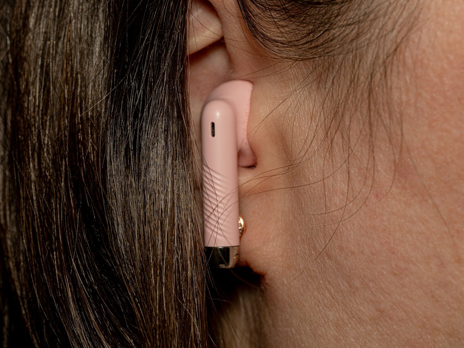A close up of a woman's ear with a pink device attached to it
