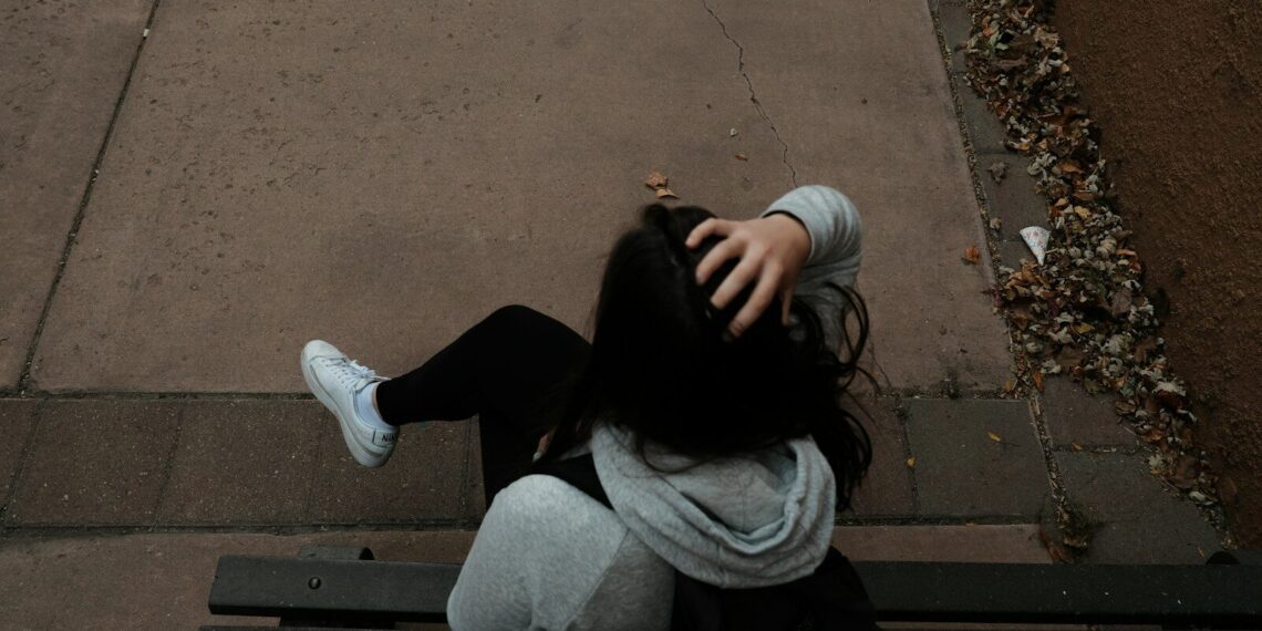 a person sitting on a bench on a sidewalk
