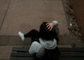 a person sitting on a bench on a sidewalk
