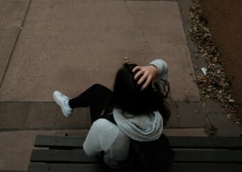 a person sitting on a bench on a sidewalk