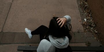 a person sitting on a bench on a sidewalk